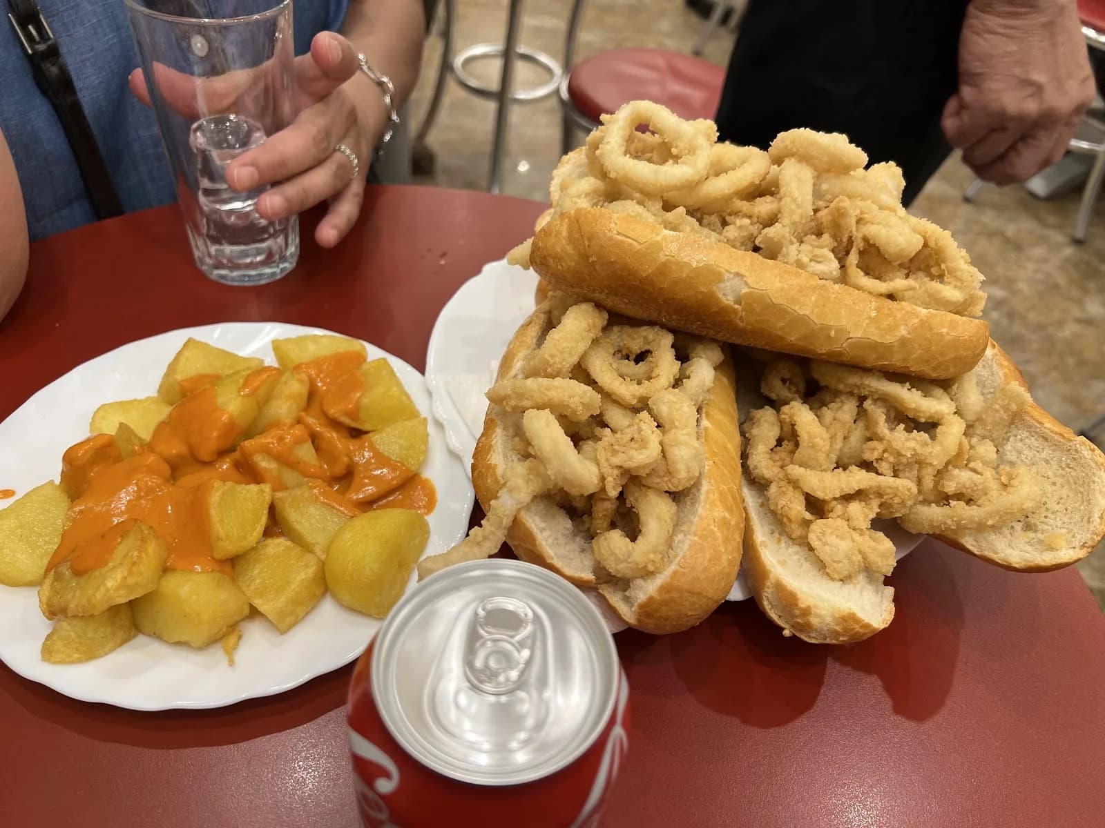 Bocadillos de calamares y patatas bravas sobre una mesa roja