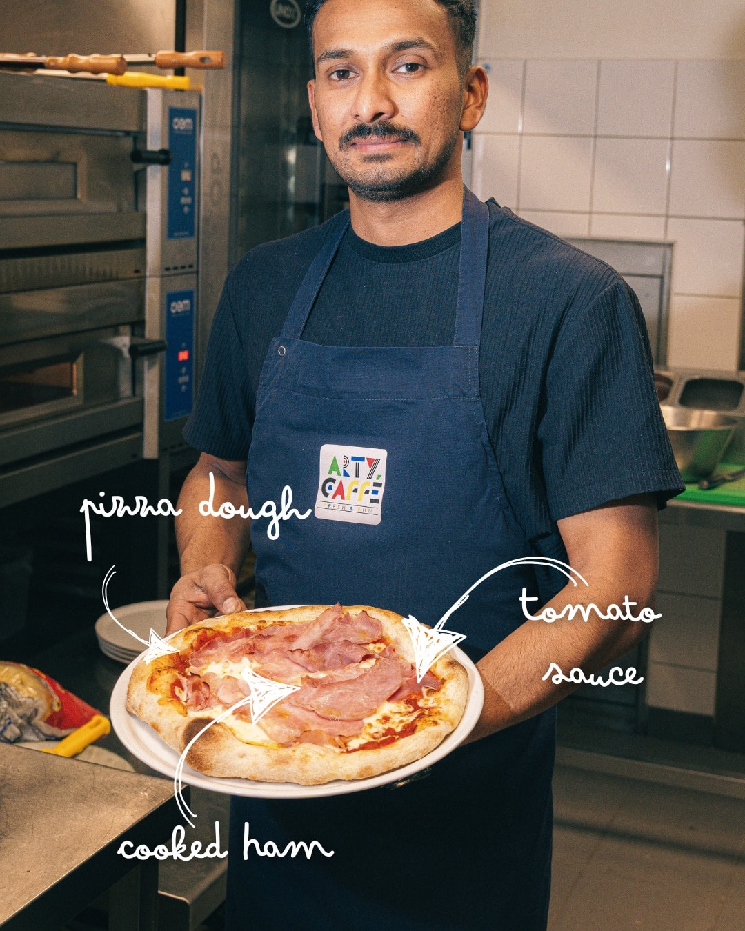 Membre de l’équipe Arty Caffé présentant une pizza préparée dans la cuisine