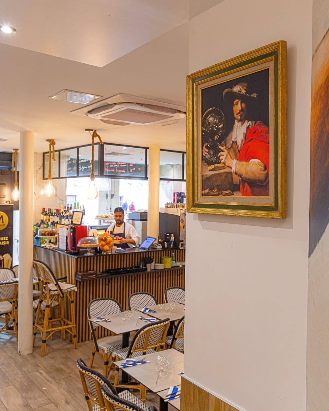 Salle de l’Arty Caffé avec tables, comptoir et tableau encadré