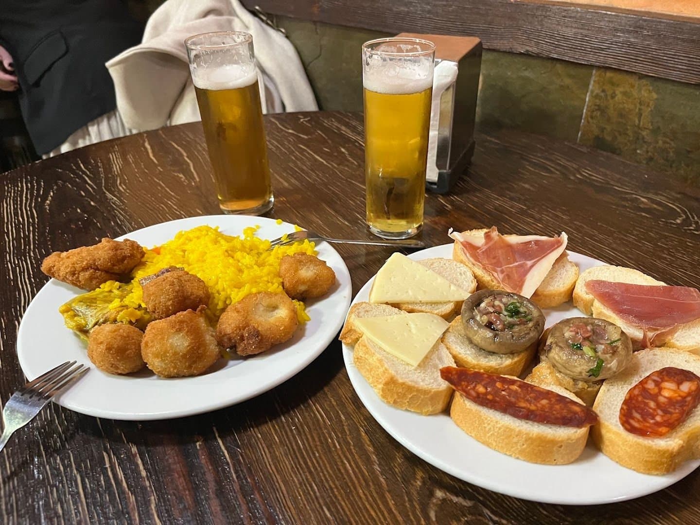 Dos cervezas y dos platos abundantes de arroz, croquetas, jamón, queso y pan en El Tigre