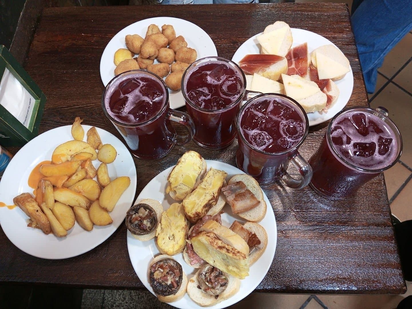 Tapas variadas, patatas y jarras de bebida en El Tigre