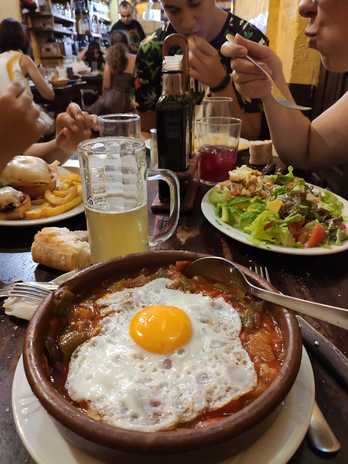 Cazuela con huevo, ensalada, cerveza y platos compartidos en Malaspina