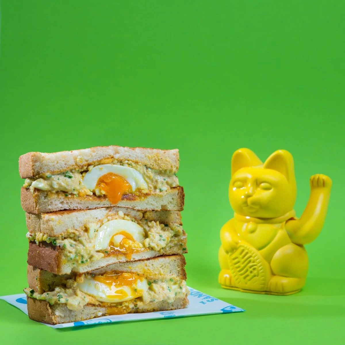Egg sando stacked beside The Sando Shop yellow lucky cat